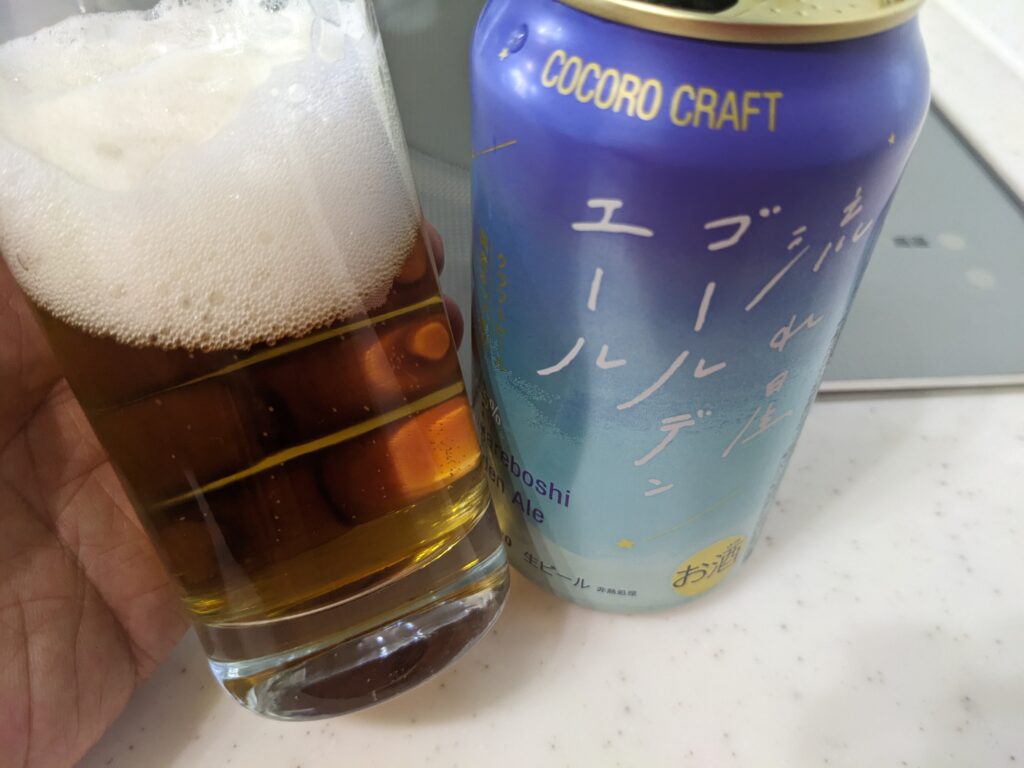 「サッポロ ココロクラフト流れ星ゴールデンエール」が入ったグラスを傾けているところ