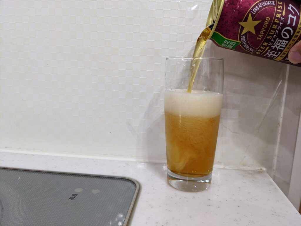 サッポロ至福のコクをグラス真ん中あたりまで注いでいるところ