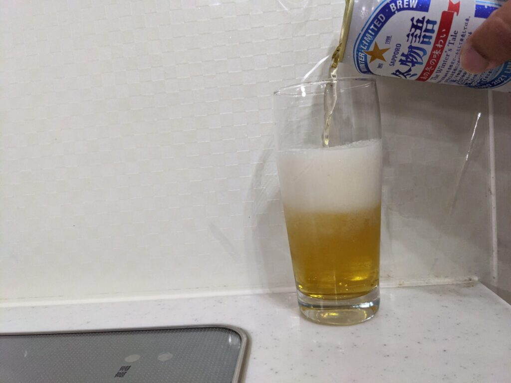 サッポロ冬物語をグラス真ん中あたりまで注いでいる