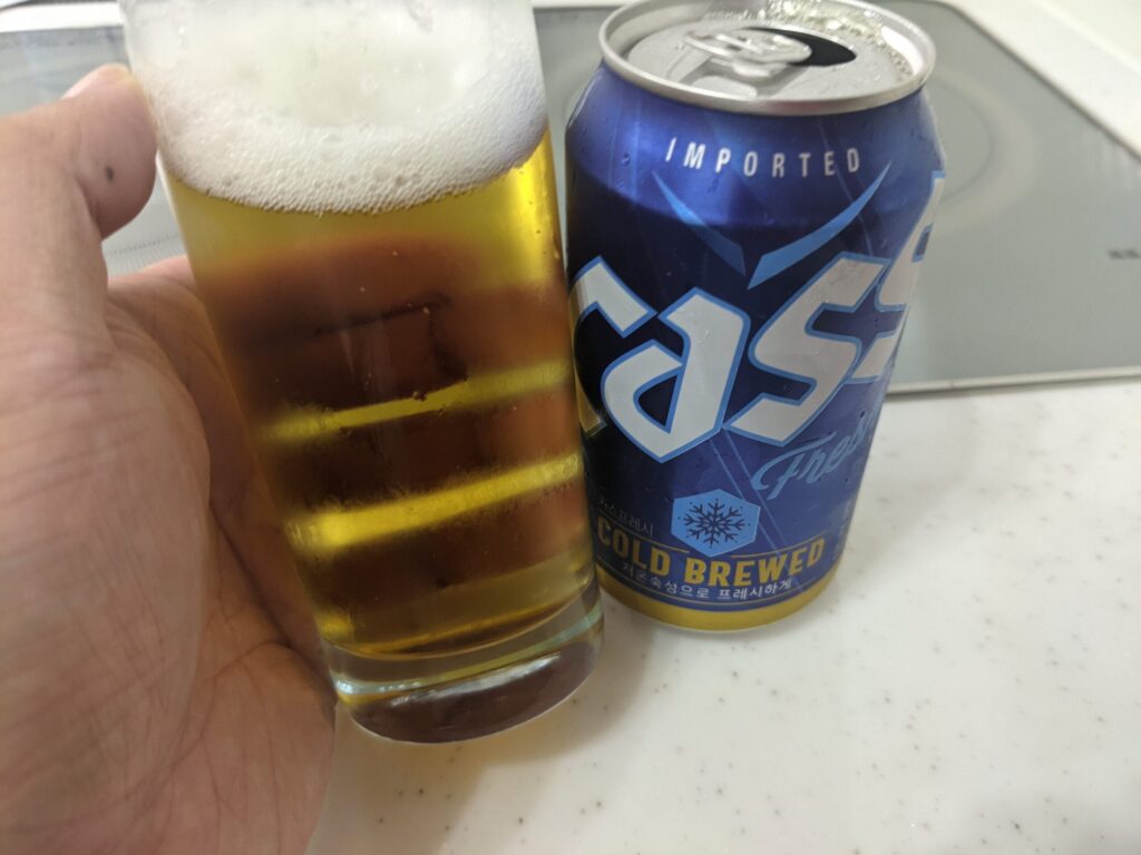 cass（カス）フレッシュビールが入ったグラスを傾けている