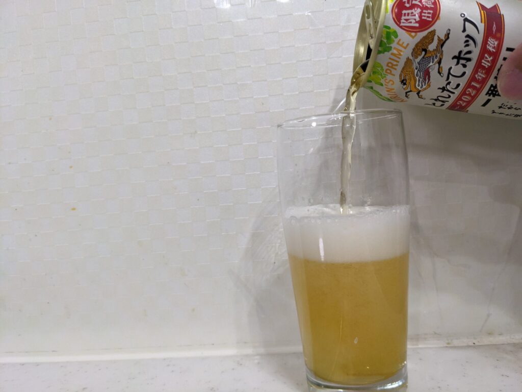 半分程グラスに「一番搾りとれたてホップ」を注ぐ