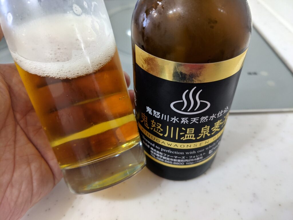 「鬼怒川温泉麦酒」が入ったグラスを傾けている