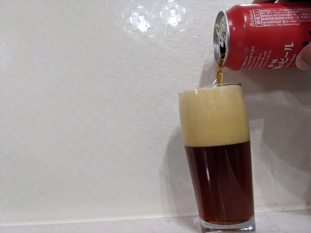 グラスいっぱいまで「悪魔のビールレッドセッションIPA」を注いでいる