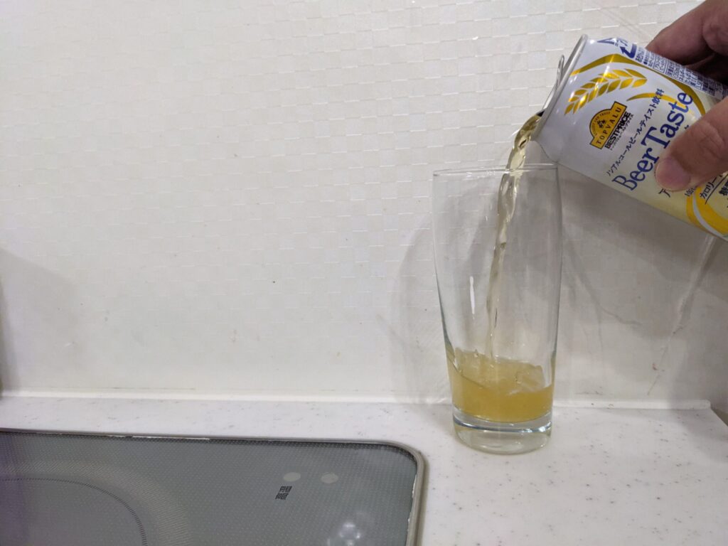 グラスにトップバリュ「Beer Taste（ビアテイスト）」を注いでいる