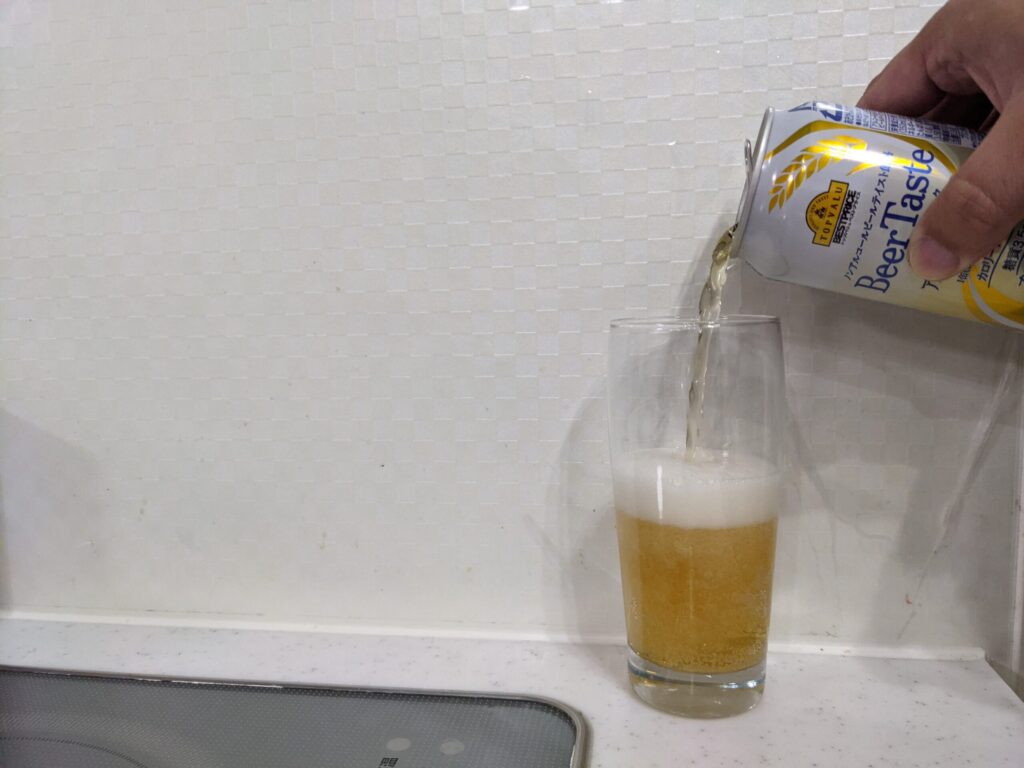 グラス半分程までトップバリュ「Beer Taste（ビアテイスト）」を注いでいる