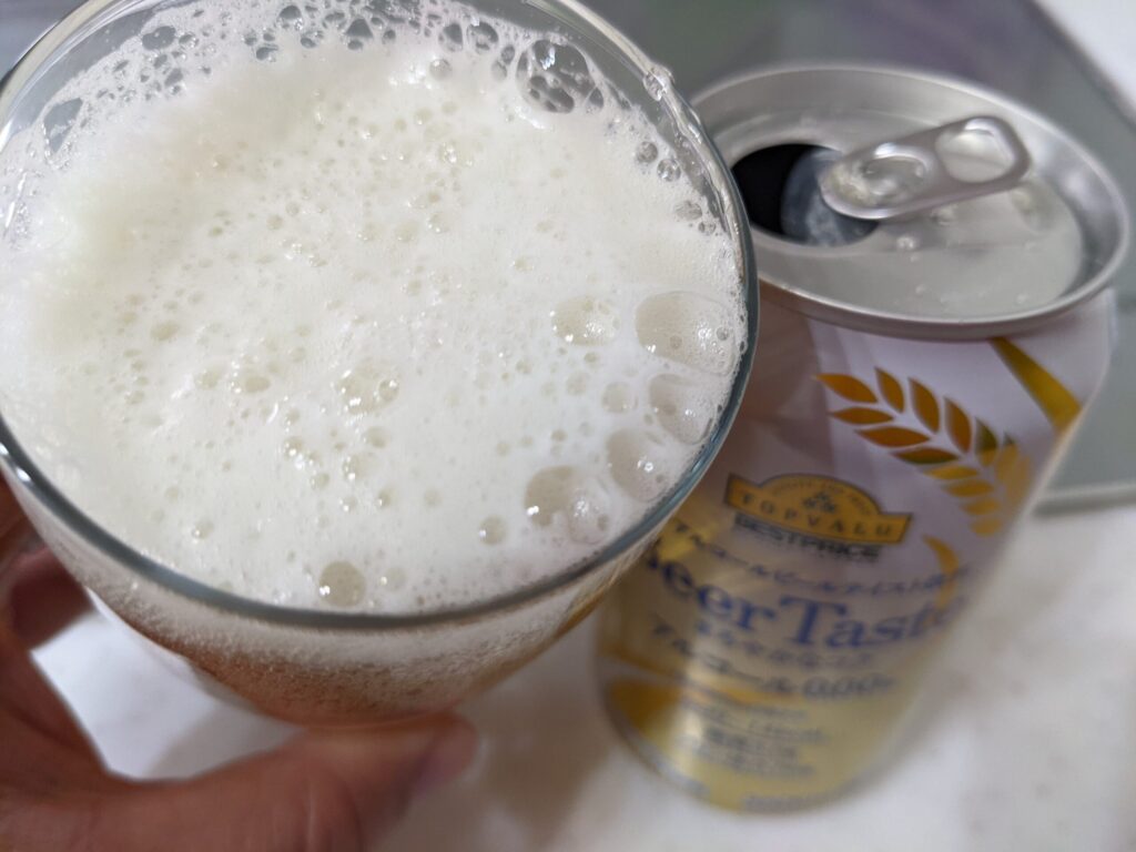 グラスに注いだトップバリュ「Beer Taste（ビアテイスト）」を飲むところ