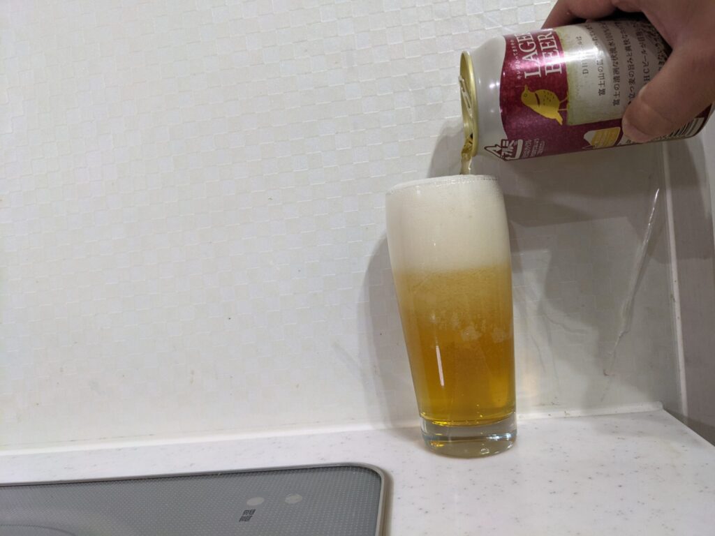 「DHCラガービール」をグラスいっぱいに注いでいる