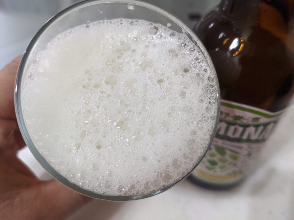 グラスに入った「ズモナビールゴールデンピルスナー」を飲むところ