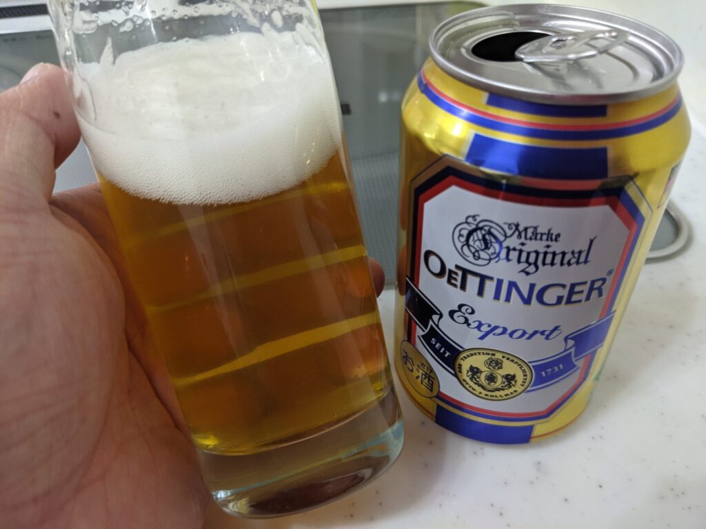 飲んでいるグラスに入った「エッティンガーエクスポルト」を傾けているところ