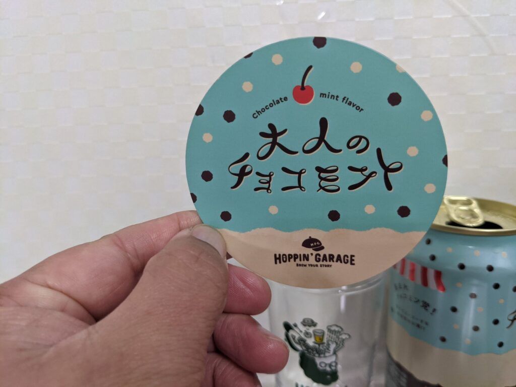 「大人のチョコミントビール」のマグネットステッカーを手で持っているところ