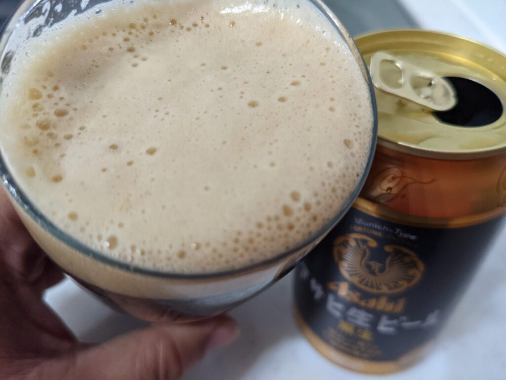 グラスに入った「アサヒ生ビール黒生」を飲むところ