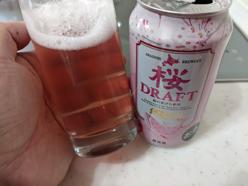 グラスに入った「網走ビール桜ドラフト」を傾けているところ