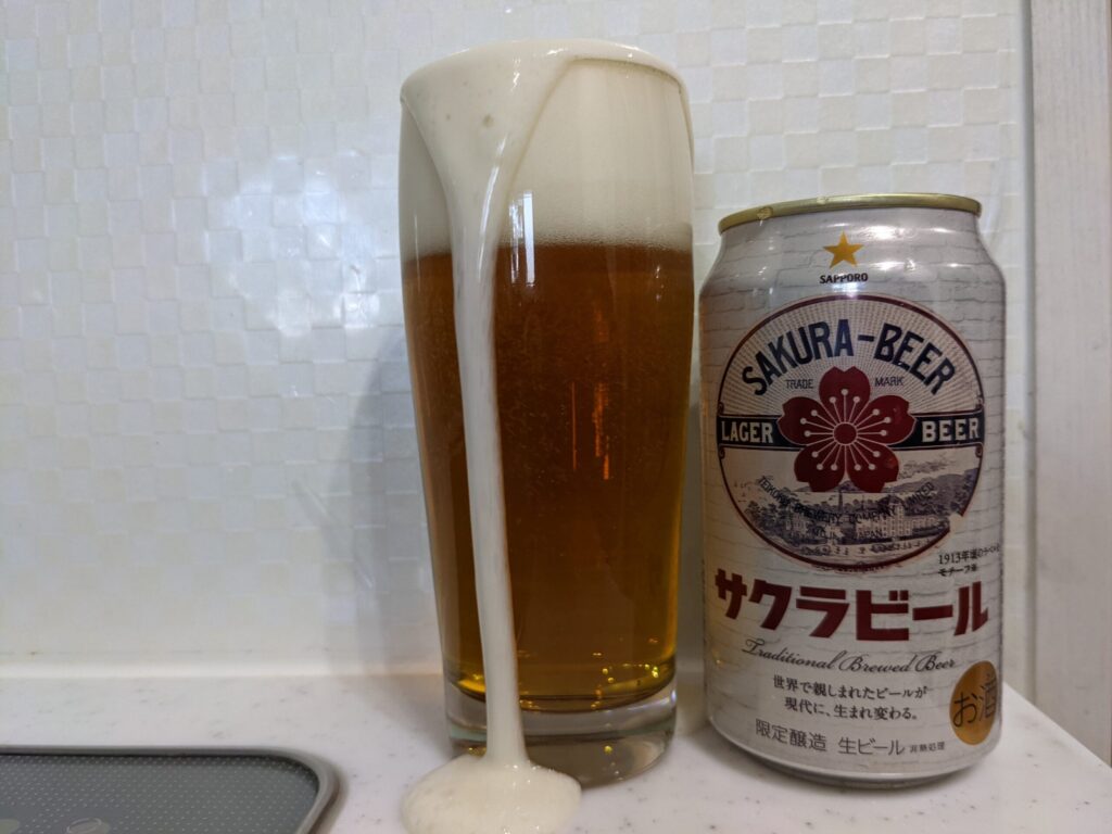グラスに注がれて泡が溢れている「サッポロサクラビール」とその缶