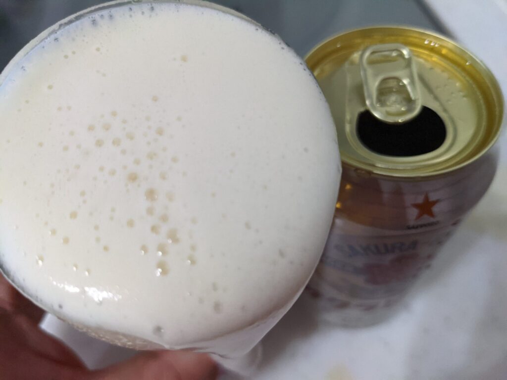 グラスに注がれた「サッポロサクラビール」を飲むところ