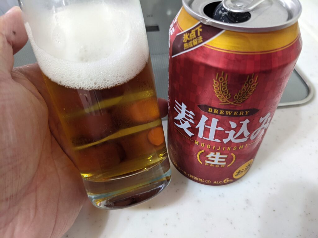 「麦仕込み（生）」が入ったグラスを傾けているところ