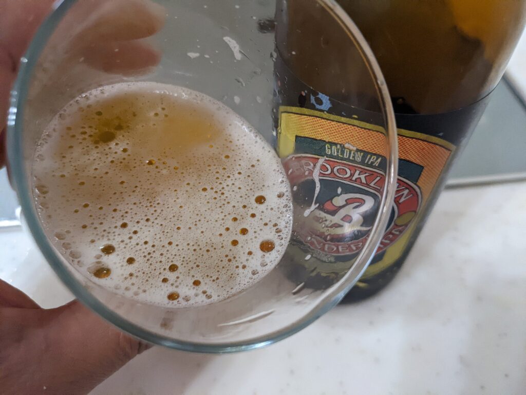 「ブルックリンディフェンダーIPA」を手前に傾けているところ