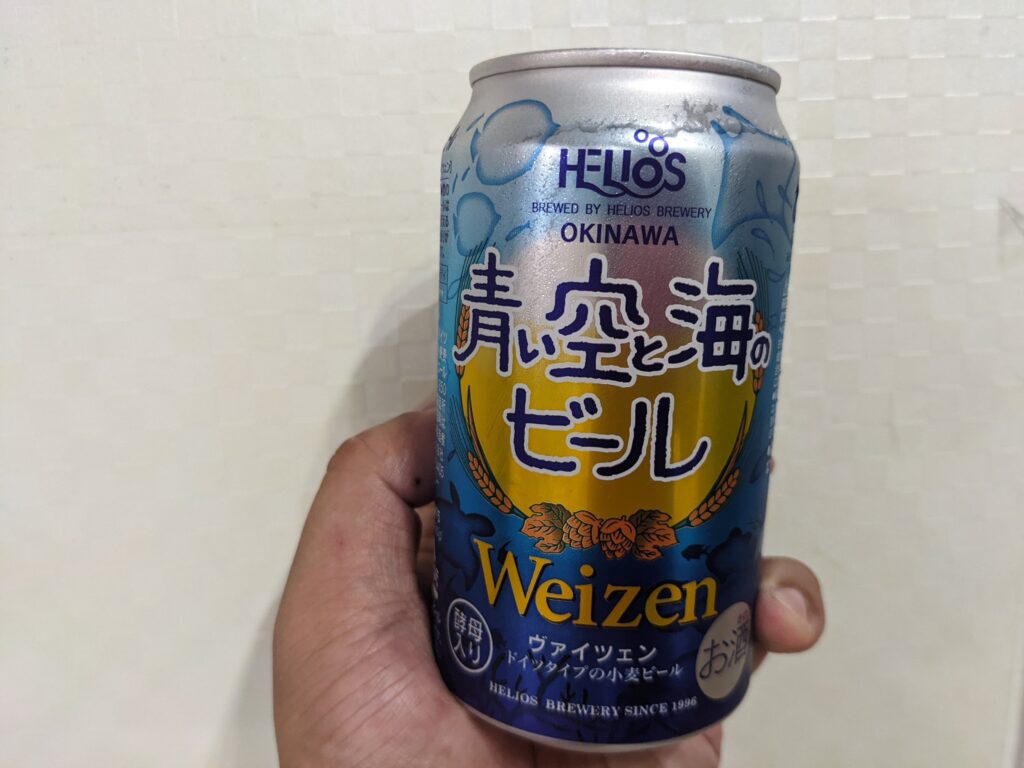 「青い空と海のビール」を手で持っている