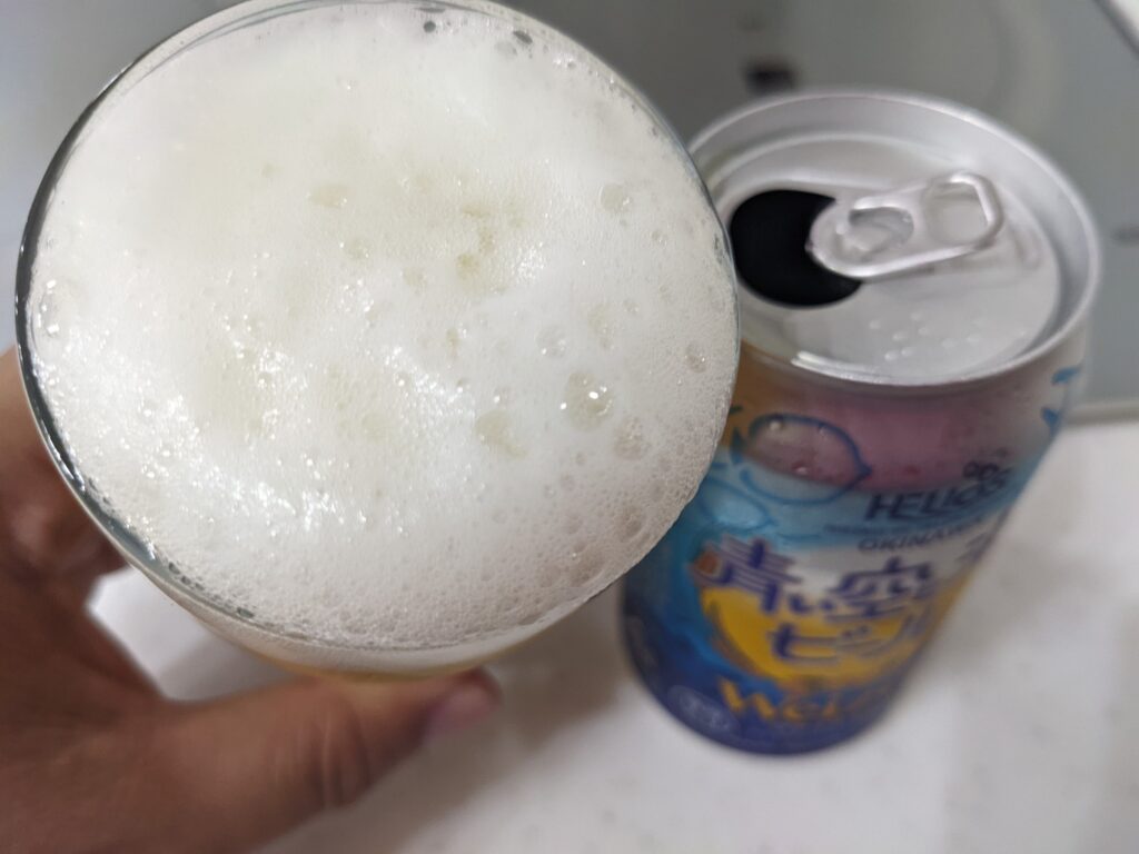 グラスに注がれた「青い空と海のビール」を飲むところ