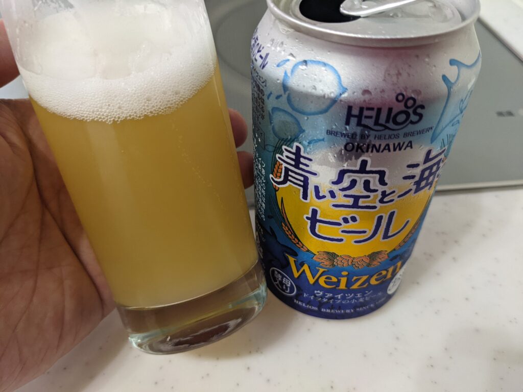 「青い空と海のビール」が入ったグラスを傾けているところ