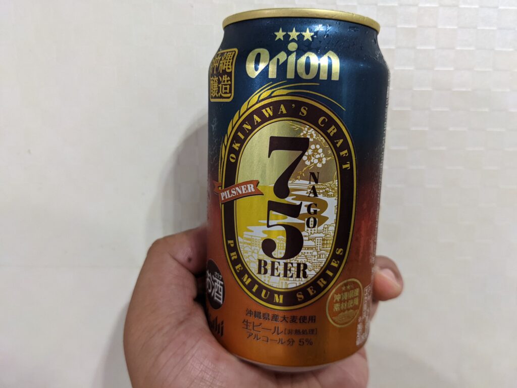 「75（名護）ビールピスルナー」を手で持っているところ