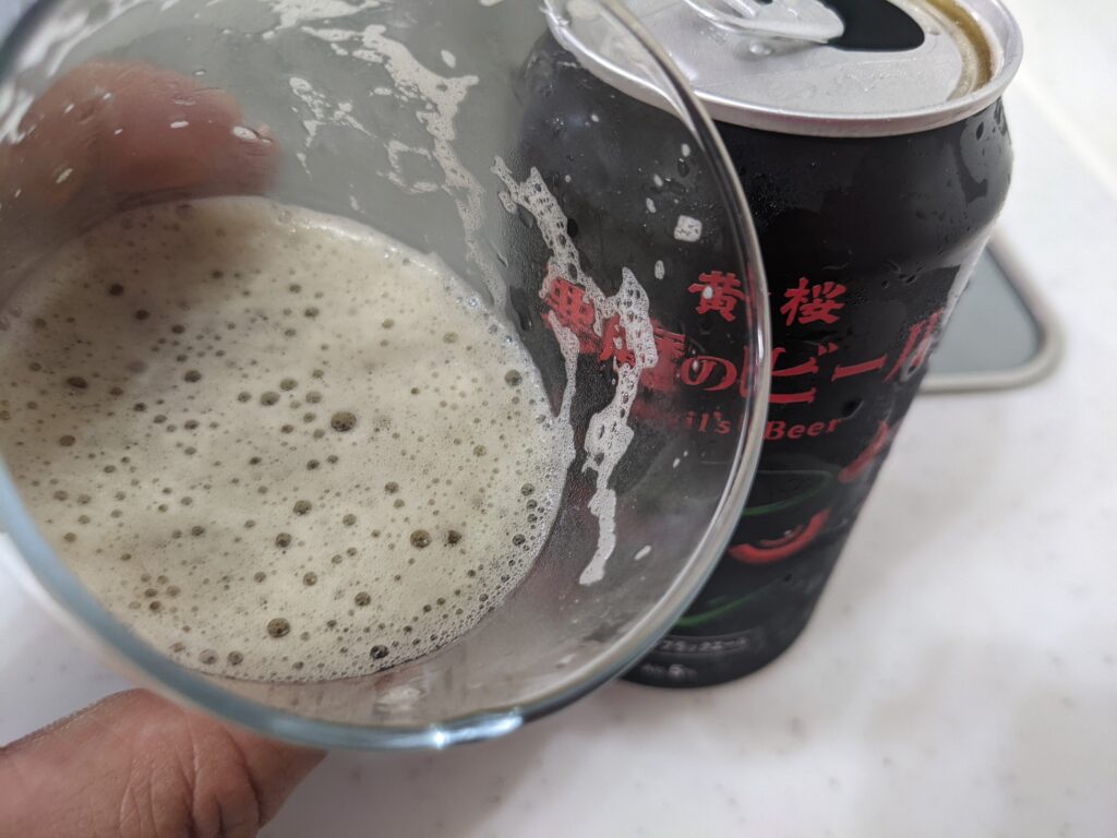 残り半分程のグラスに入った「悪魔のビール【黒】アメリカンブラックエール」