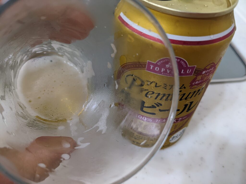 最後の一口程度のグラスに入った「トップバリュ」プレミアム生ビール