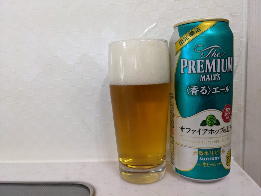 「サファイアホップの恵み（プレモル香るエール）」が注がれたグラスとその缶