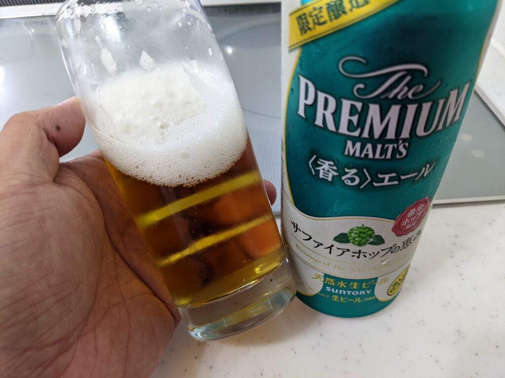 「サファイアホップの恵み（プレモル香るエール）」が入ったグラスを傾けているところ