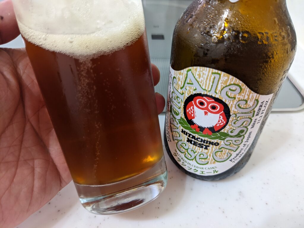 「ジャパニーズクラシックエール常陸野ネストビール」が入ったグラスを傾けているところ