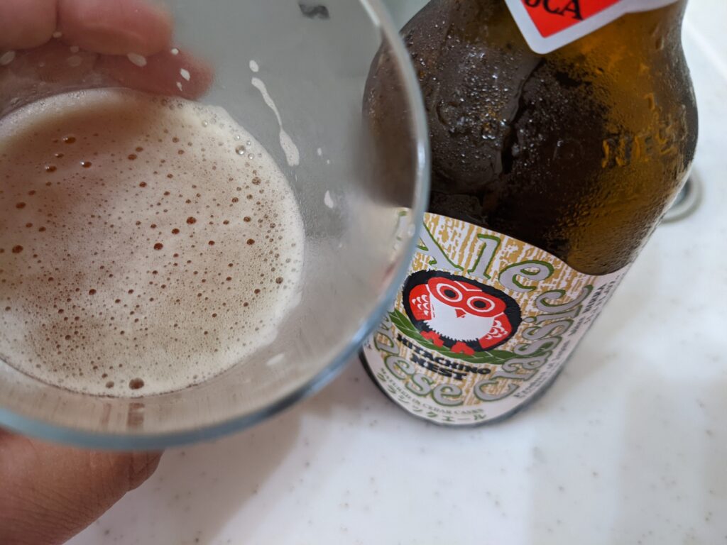 「ジャパニーズクラシックエール常陸野ネストビール」が入ったグラスを手前に傾けているところ