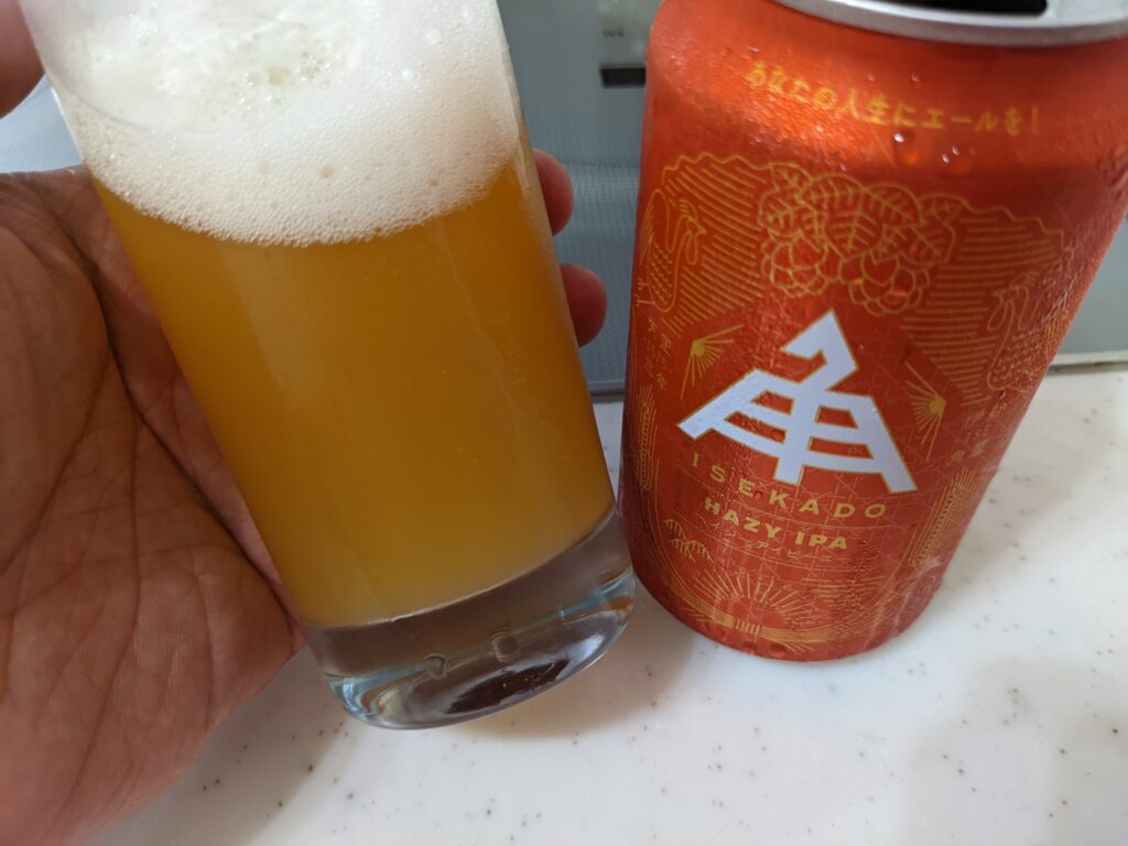 「イセカドヘイジーIPA」が入ったグラスを傾けているところ