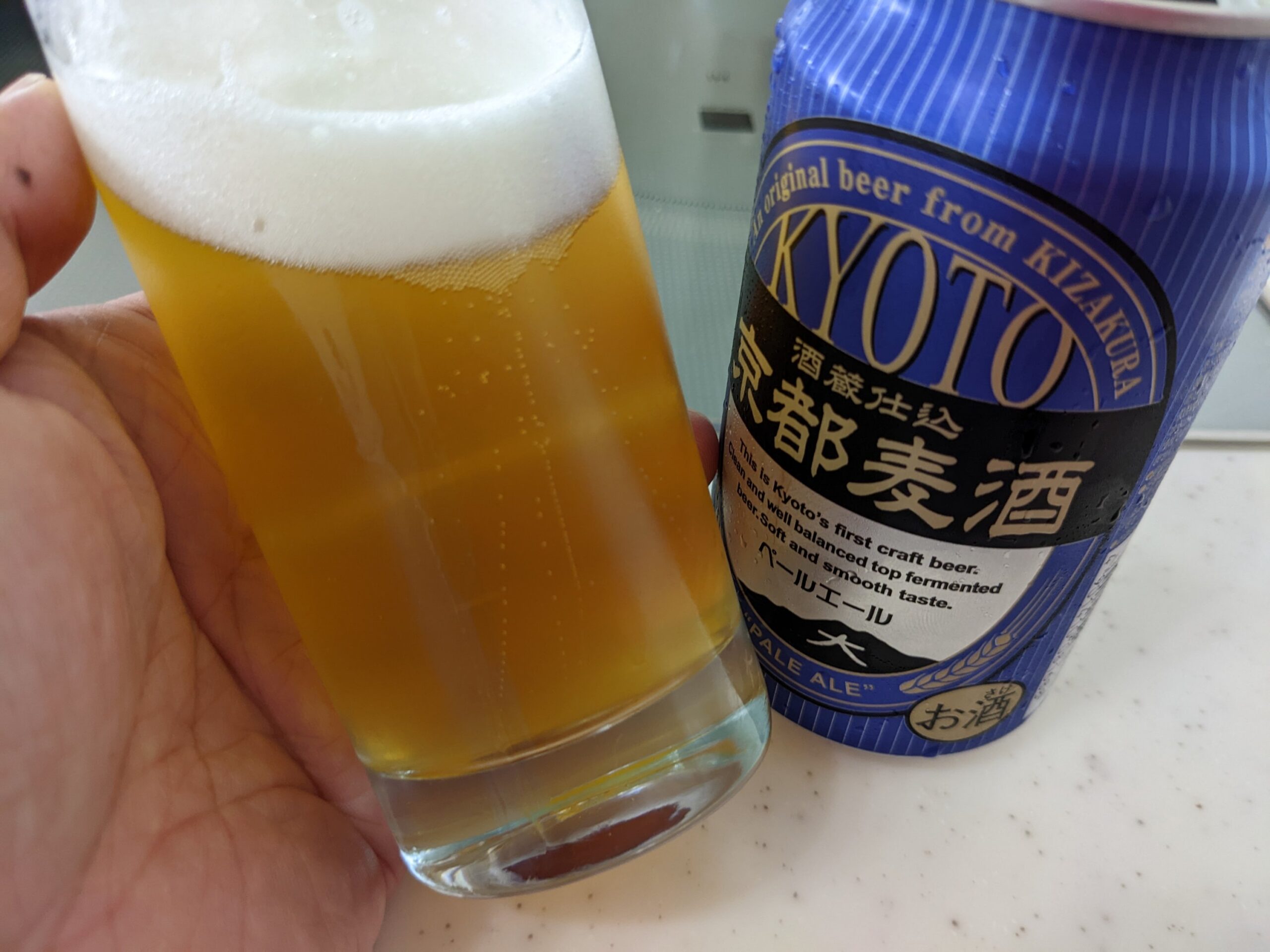 「京都麦酒ペールエール」が入ったグラスを傾けているところ