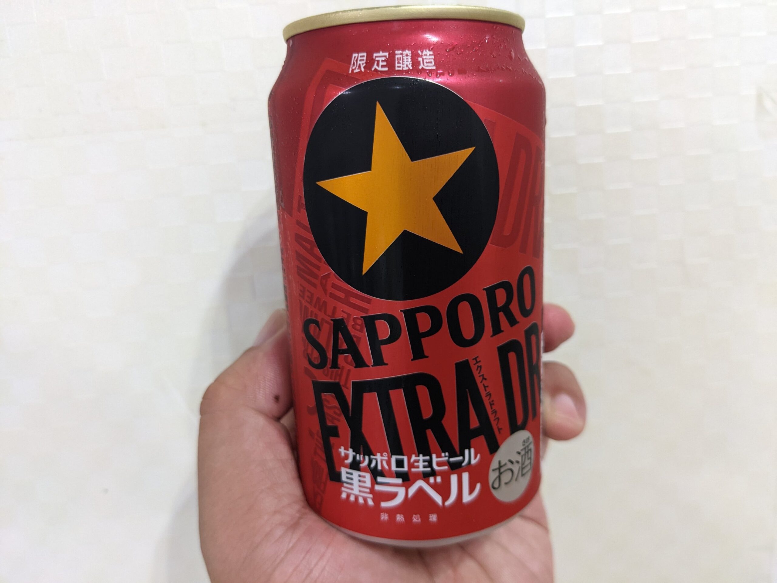 「黒ラベルエクストラドラフト」を手で持っている
