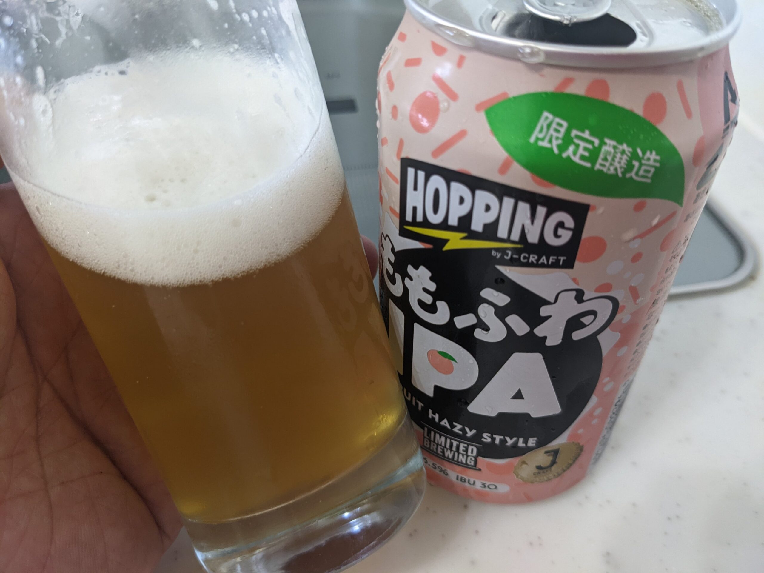 「ももふわIPA（J-CRAFT HOPPING）」が入ったグラスを傾けているところ