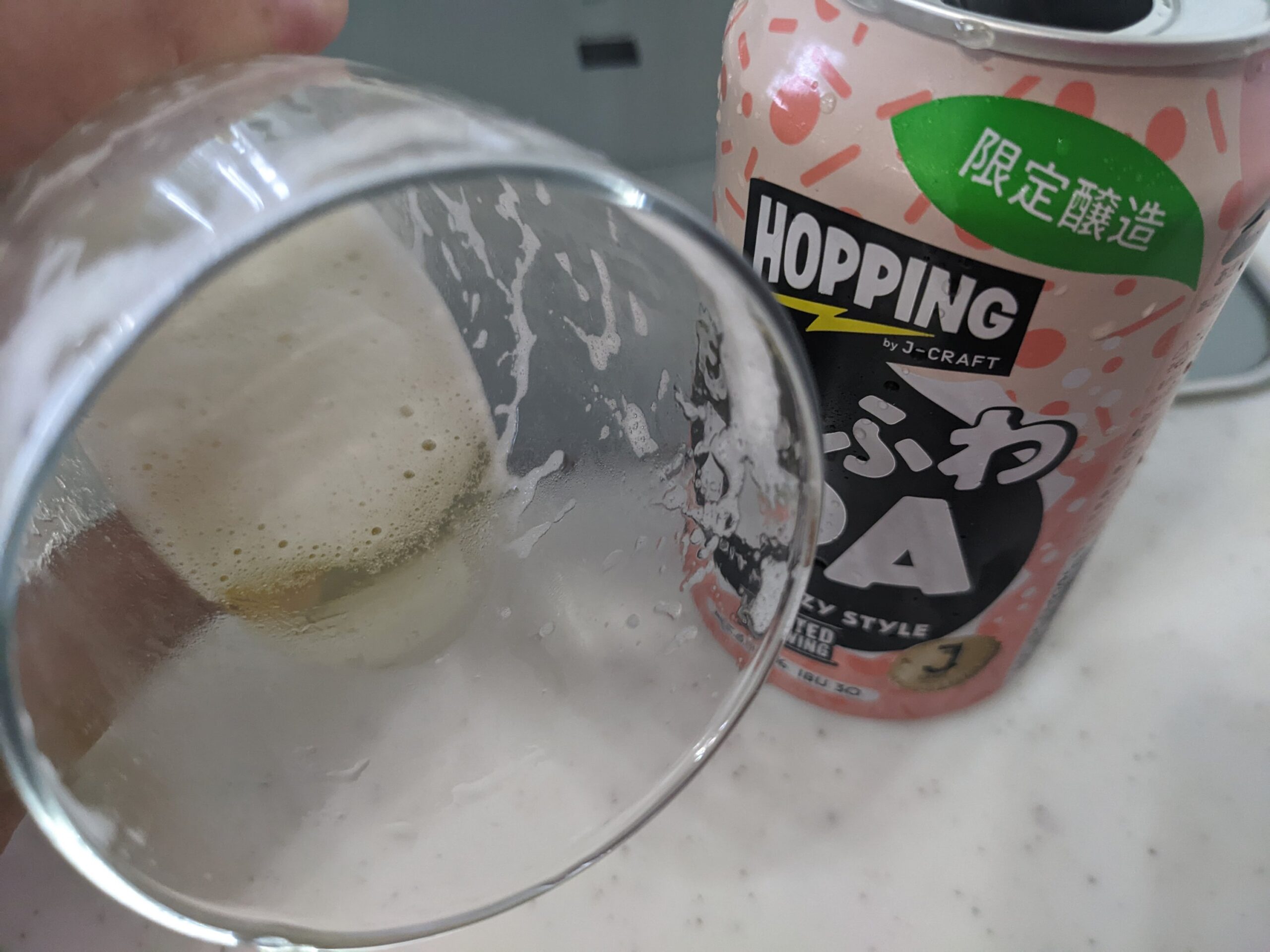 「ももふわIPA（J-CRAFT HOPPING）」が入ったグラスを手前に傾けているところ