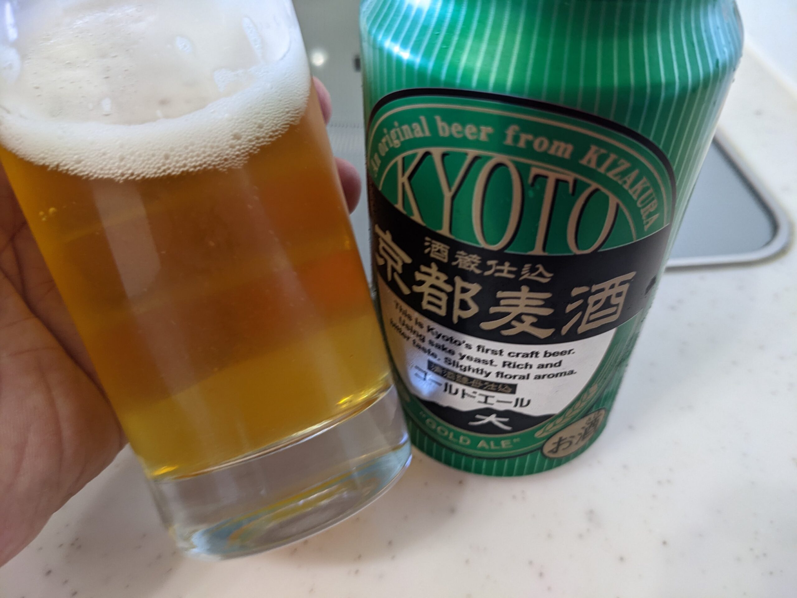 「京都麦酒ゴールドエール 」が入ったグラスを傾けているところ