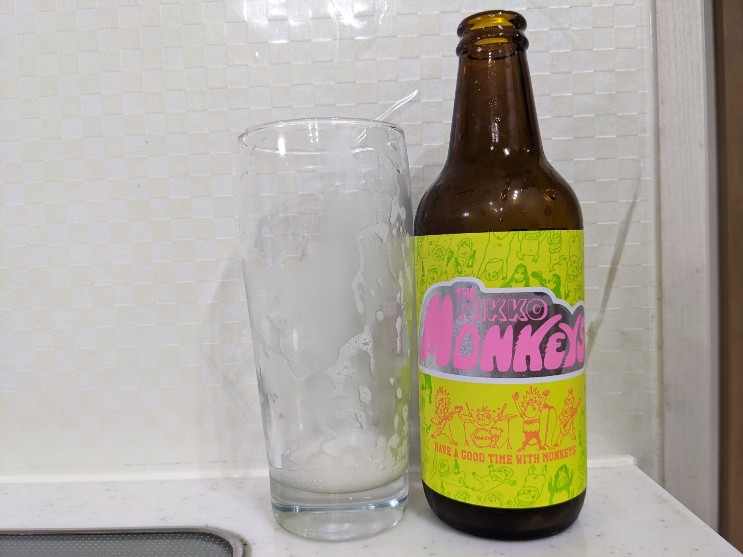 「ザ・ニッコーモンキーズプレミアムラガー」を飲み終えたグラスとその空き瓶