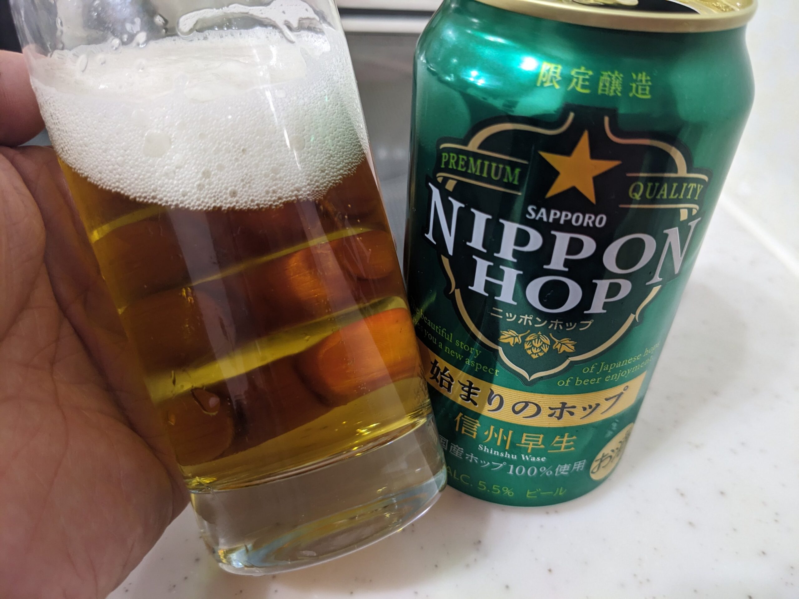 「ニッポンホップ始まりのホップ信州早生」が入ったグラスを傾けているところ