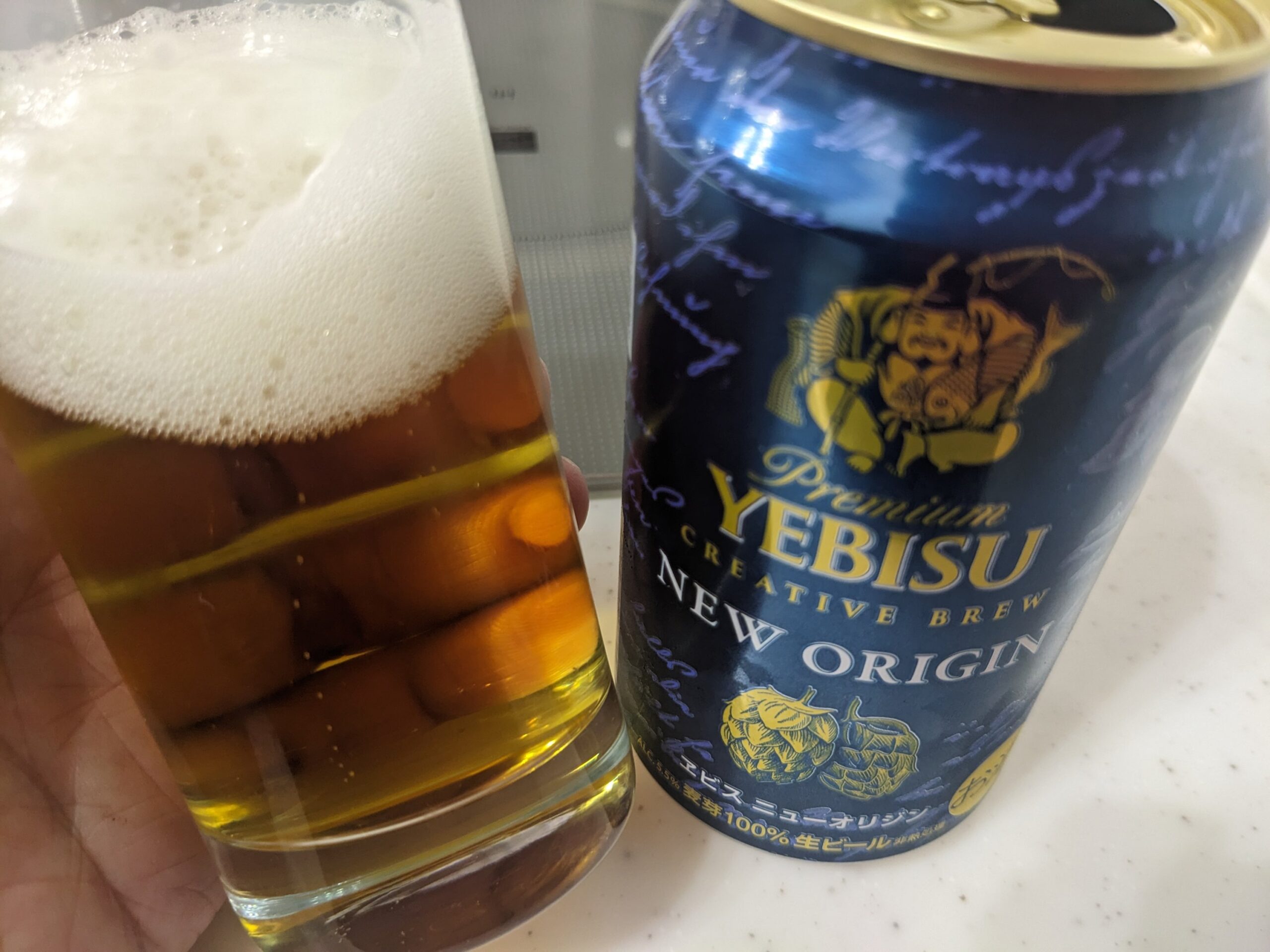「ヱビスニューオリジン」が入ったグラスを傾けているところ